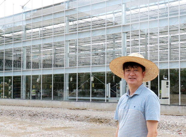 푸르메소셜팜 온실 앞에서 포즈를 취하고 있는 김병두 대표