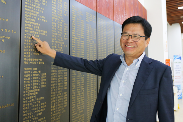 푸르메재단 기부벽에서 자신의 이름을 가리키며 활짝 웃고 있는 오산택 대표