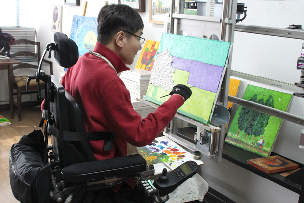 손목에 붓을 고정시키고 그림을 그리는 탁용준 화백