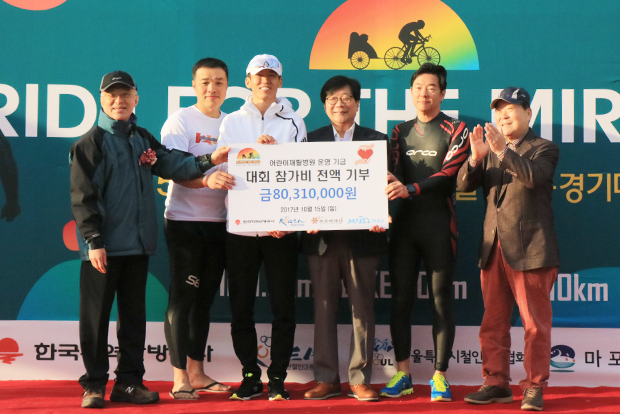 철인 1,006명의 대회 참가비 8,031만 원 기부금 전달식에서 강지원 푸르메재단 이사장, 은총아빠 박지훈 씨, 션 푸르메재단 홍보대사, 김경원 한국지역난방공사장, 박석원 대한철인3종경기협회장, 박홍섭 마포구청장