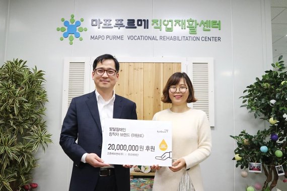 지난 22일 교촌에프앤비 장규식 마케팅∙기획본부장(왼쪽)이 이민희 마포푸르메 직업재활센터장에게 ‘2019 허니 릴레이 기부 캠페인’을 통해 마련한 기부금을 전달후 기념촬영을 하고 있다.