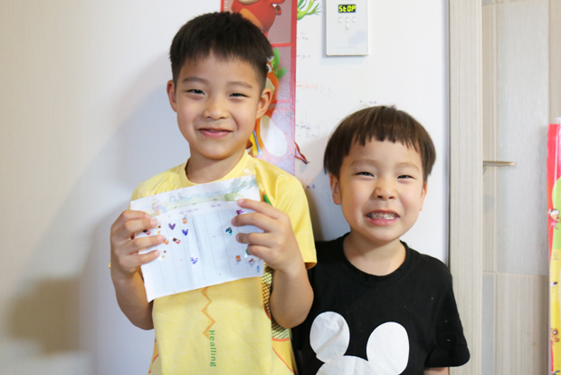 ▲ 형 민우와 동생 민재가 칭찬스티커 종이를 펼치고 활짝 웃고 있다.