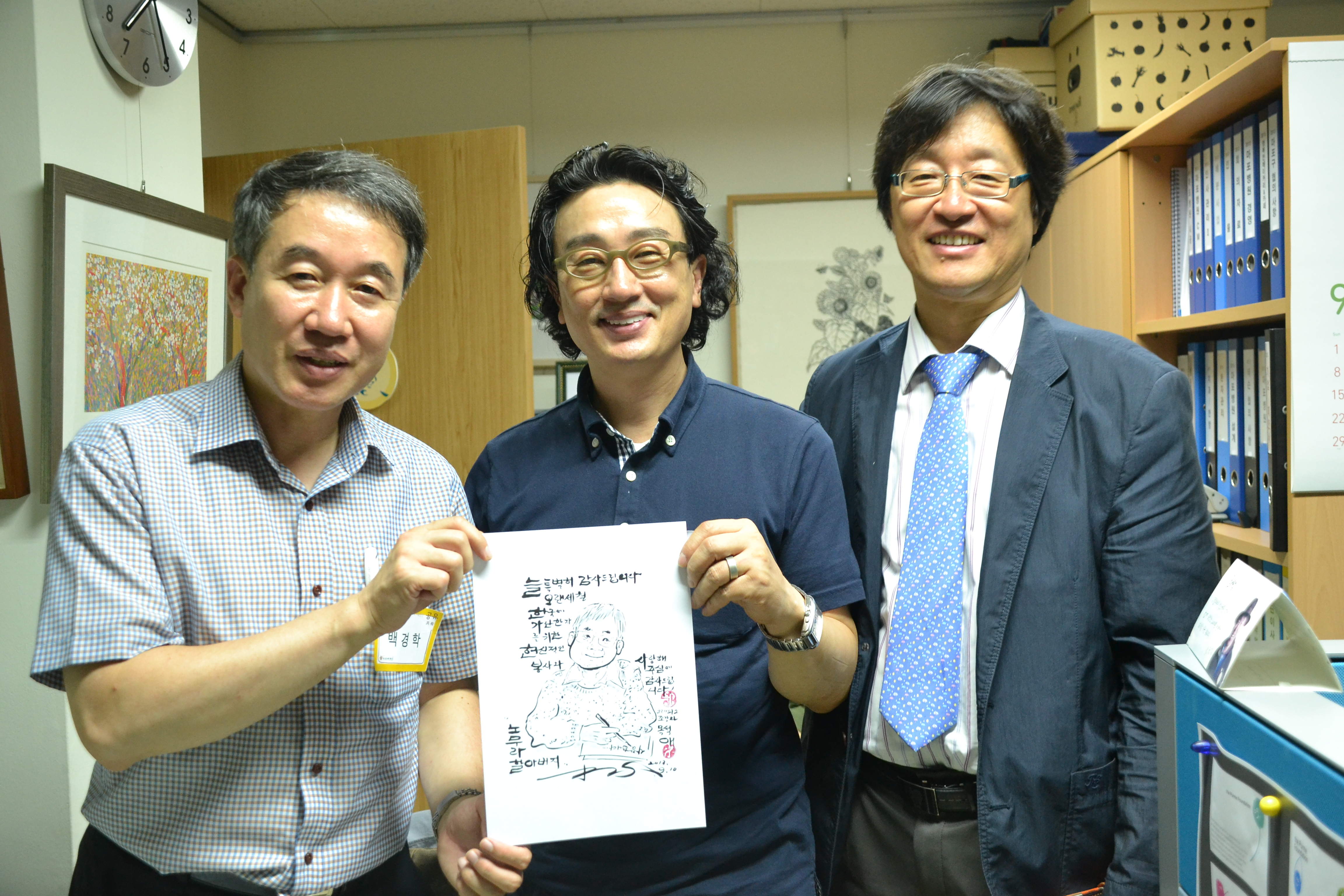 ▲ 백경학 상임이사, 목석애 화백, 차경환 대표가 함께 웃는 모습. 사진 속 그림은 일본의 빈민운동가 노무라 모토유키.