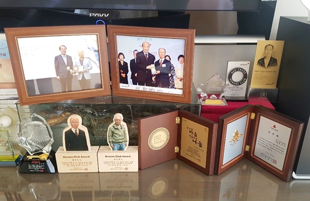 여러 단체에서 받은 감사패가 자택의 테이블을 가득 채우고 있다.