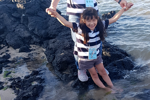바닷물에 발을 담그고 환하게 웃고 있는 다연이