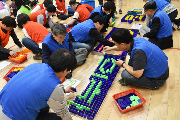 서로 격려하고 위로하며 도미노 블록을 함께 쌓고 있는 중간관리자들