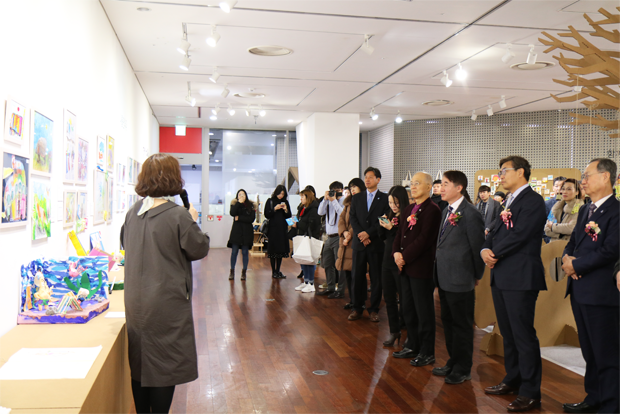 전시회 오프닝 행사에서 전시 설명을 듣고 있는 관계자들