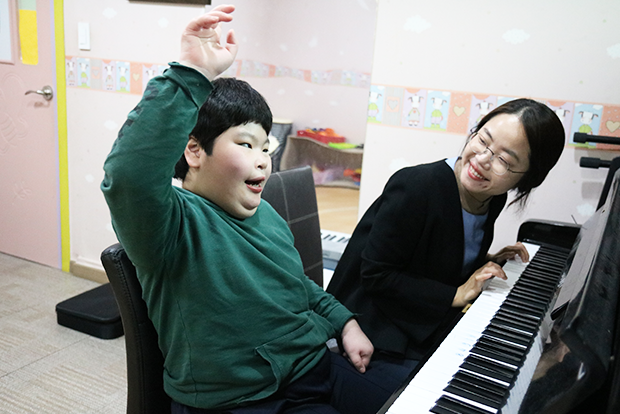 음악치료사의 피아노 연주에 맞춰 노래를 부르고 있는 지우
