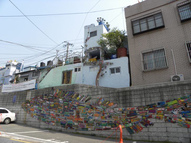 ▲ 벽면에 설치된 ‘골목을 누비는 물고기’ 작품은 물고기 모양의 나무판들로 이뤄져 있다.