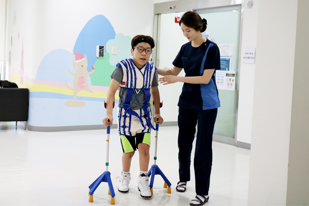 집중운동치료 때 지팡이를 짚고 걷는 연습을 하는 주언이