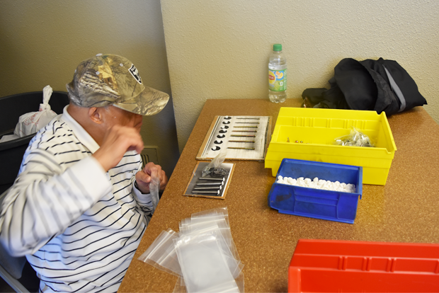 샘플 그림판에 부품을 올려놓고 개수를 확인하는 근로자