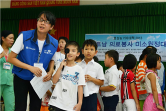 ▲ 베트남 호치민 인근 지역 주민들에게 무상 진료 서비스를 제공하는 ‘미소원정대’.  파란색 효성 조끼를 입은 베트남 직원이 어린이의 안과 검진을 돕고 있는 모습